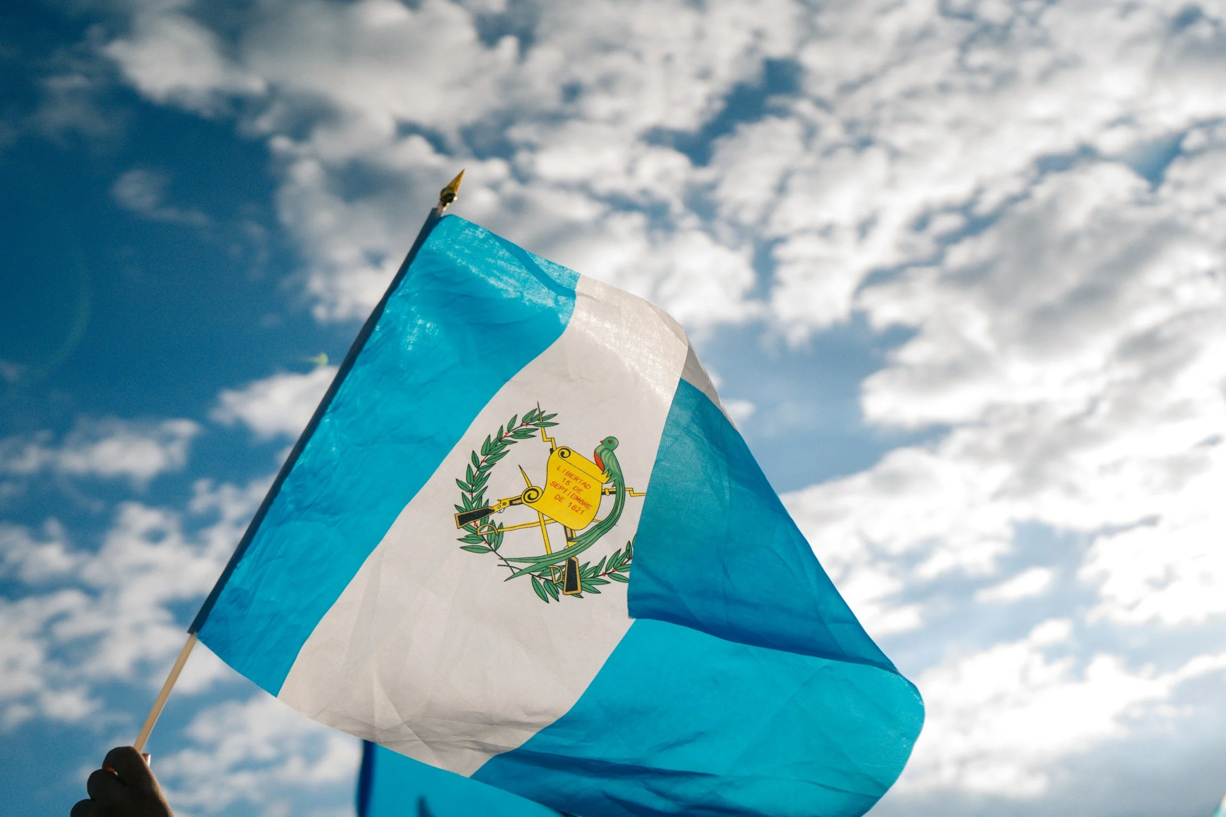 A person holding the flag of Guatemala
